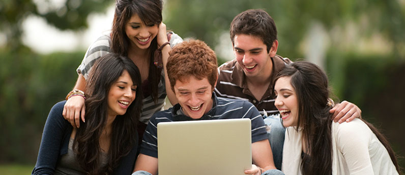 A group of students huddled around a laptop